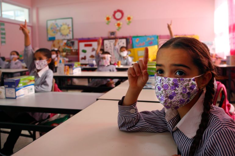 Palestinians elementary school students wearing protective face masks, gesture in their classroom amid the coronavirus pandemic on the first day of class at United Nations-run school in the West Bank city of Ramallah, Sunday, Sept. 6, 2020.(AP Photo/Majdi Mohammed)