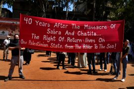 Palestinian activists hold a banner to commemorate the 40th anniversary of the Sabra and Shatila massacre at the mass grave of its victims, in Beirut, Lebanon, Sept. 16, 2022