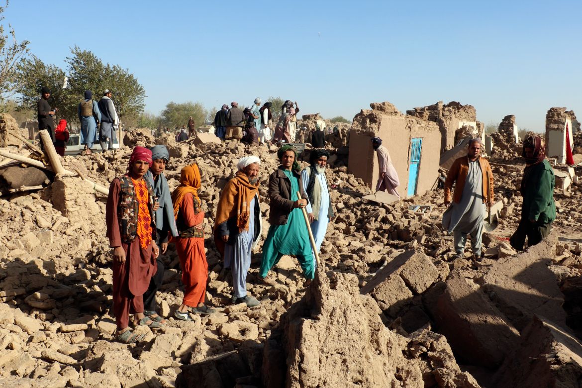 Afghans stand in a courtyard of their destroyed homes after an earthquake in Zenda Jan district in Herat province