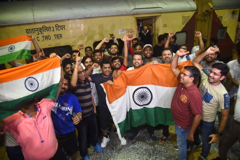 Indian cricket fans carrying national flags shout slogans as they board a special train run by Indian railways