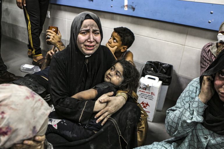 Palestinians wounded at al-Ahli hospital in Gaza sit on the floor at al-Shifa hospital following a deadly air strike blamed on Israel [Abed Khaled/AP]