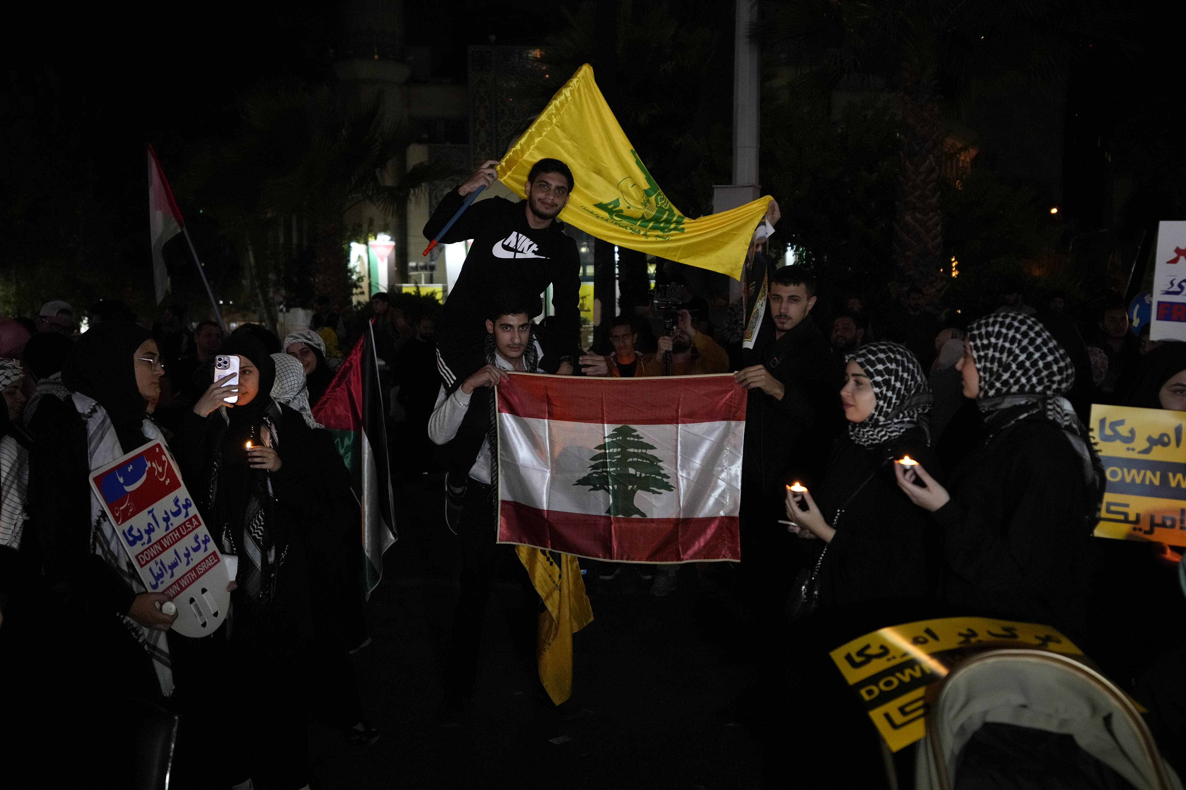 Lebanese students, living in Iran, hold Lebanon's militant Hezbollah group flag, top, and their country's national flag during a pro-Palestinian gathering at the Felestin (Palestine) Sq. in Tehran, Iran