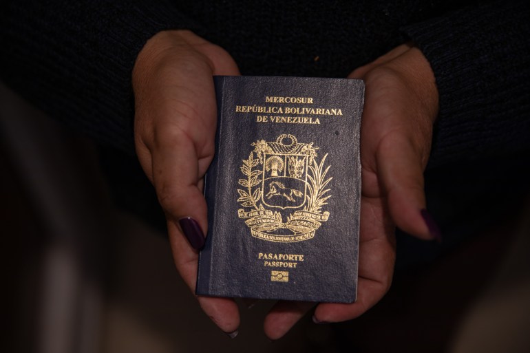Two hands cup a Venezuelan passport, embossed with gold lettering.