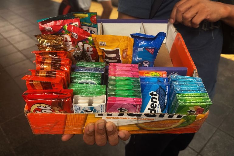 A person holds out a tray of candy, with Trident gum, Kit Kats and M&Ms.
