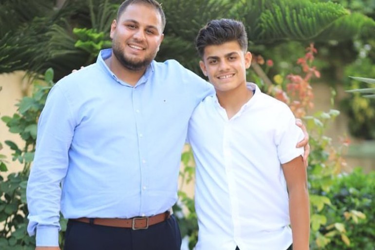 Hamza stands with his arm around his younger brother Mahmoud in a garden
