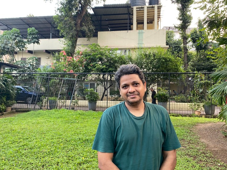 Harish Iyer poses for a photo in front of a building