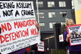 Protesters holding up a sign saying 'seeking asylum is not a crime' and 'end mandatory detention'