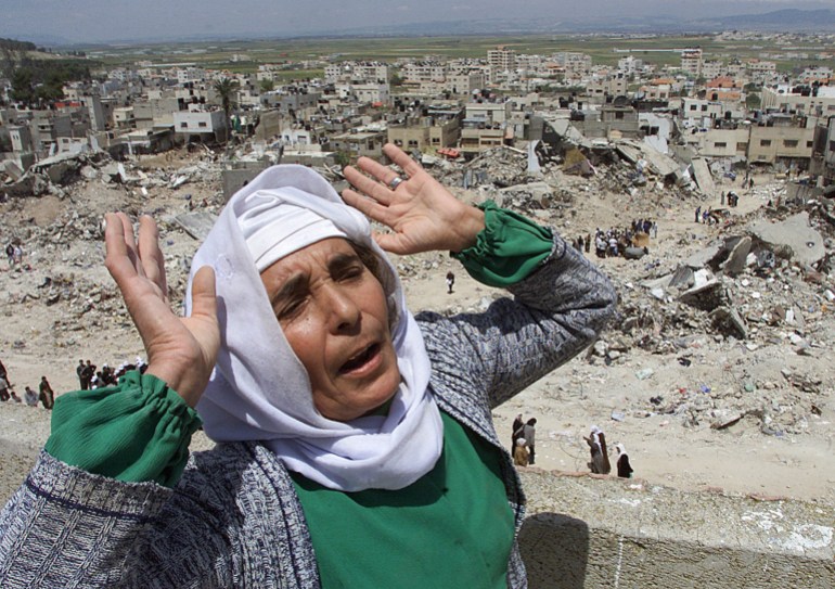 A Palestinian woman gestures on top of her house in the destroyed Jenin refugee camp in the northern West Bank, April 28, 2002. A U.N. mission to find out what happened during Israel's three weeks military operation in Jenin refugee camp is waiting in Geneva for a green light to depart to the region.