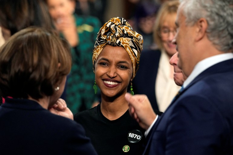 Representative Ilhan Omar smiles as she stands among colleagues in Congress