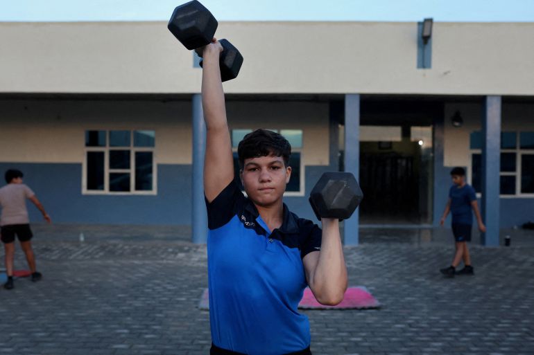 Pinky, 17, lifts dumbbells during morning fitness and practice session, on the playground at the Altius wrestling school in Sisai, Haryana, India.