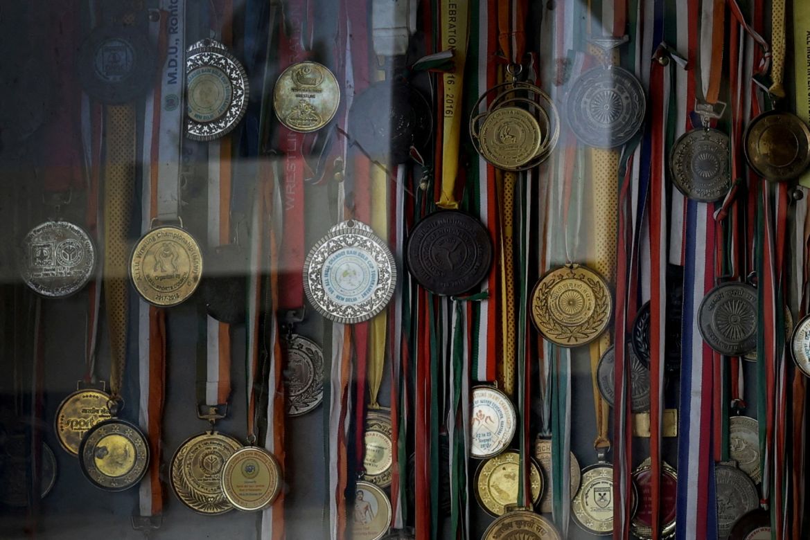 Medals hang inside a cabinet on a wall at the Altius wrestling school in Sisai, Haryana, India.