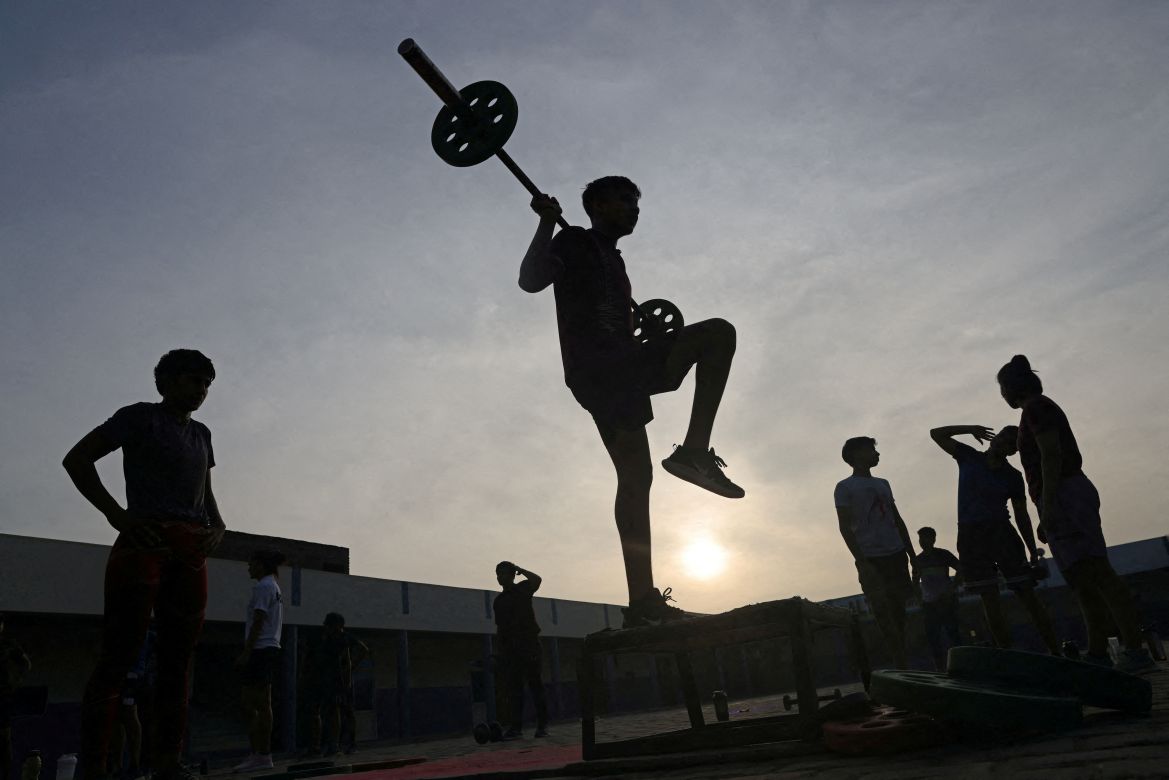 Aayush, 15, one of the three male students in Altius wrestling school, lifts weights and exercises during the morning fitness and practice session, on the playground at the school in Sisai, Haryana, India.