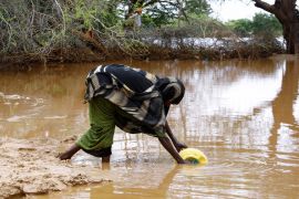 A woman collects flood water following heavy rains that have led the Juba river to overflow and flood large swathes of land in Dolow, Somalia