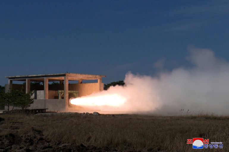 A solid fuel missile being tested in a concrete bunker. There is flame and smoke coming out of it.