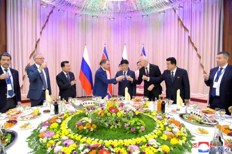 North Korean government representatives welcome a Russian delegation led by natural resources minister Alexander Kozlov during a banquet in Pyongyang. They are holding a toast around a lavishly decorated table