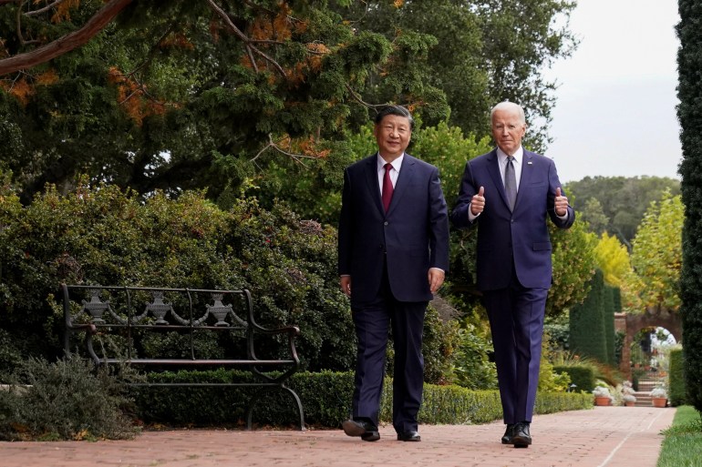 Biden giving a thumbs up as he walks with Xi in the garden of the Filoli estate