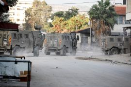 Israeli military vehicles move through a street after Israeli forces raided the Jenin refugee camp in the Israeli-occupied West Bank.