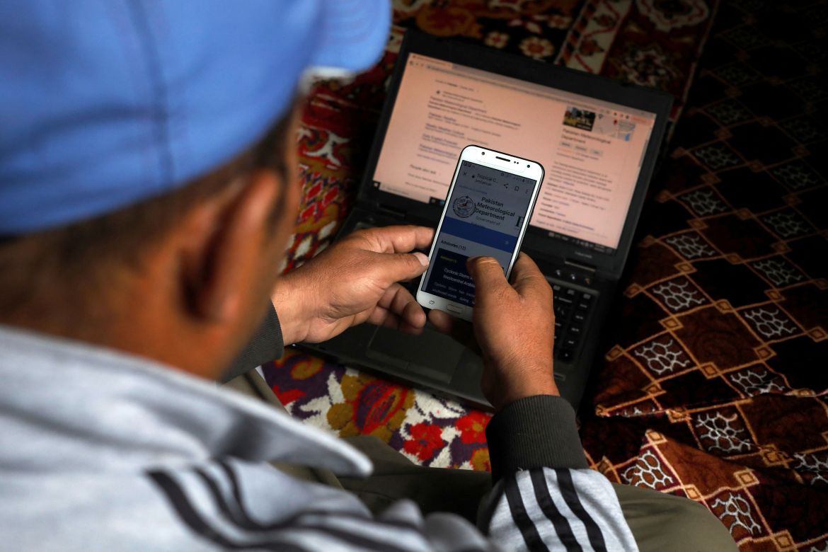 Tariq Jamil, 51, chairman of the Community Based Disaster Risk Management Centre, monitors a metrological website on his mobile phone and laptop, at home in Hassanabad village, Hunza valley.