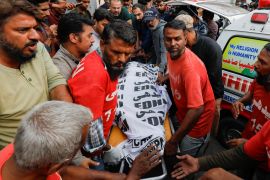 Rescue workers move the body of a man who was killed in a fire in Pakistan