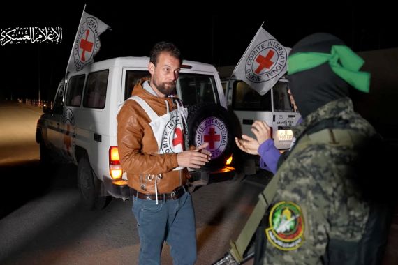 A Hamas militant interacts with members of the International Committee of the Red Cross, as Hamas militants hand over hostages who were abducted during the October 7 attack on Israel to members of the International Committee of the Red Cross, as part of a hostages-prisoners swap deal between Hamas and Israel amid a temporary truce, in an unknown location in the Gaza Strip, in this screengrab taken from video released November 27, 2023. Hamas Military Wing/Handout via REUTERS THIS IMAGE HAS BEEN SUPPLIED BY A THIRD PARTY. WATERMARK FROM SOURCE.