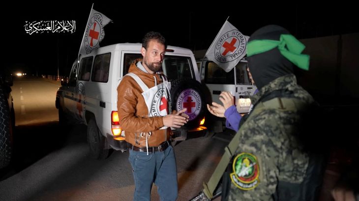 A Hamas militant interacts with members of the International Committee of the Red Cross, as Hamas militants hand over hostages who were abducted during the October 7 attack on Israel to members of the International Committee of the Red Cross, as part of a hostages-prisoners swap deal between Hamas and Israel amid a temporary truce, in an unknown location in the Gaza Strip, in this screengrab taken from video released November 27, 2023. Hamas Military Wing/Handout via REUTERS THIS IMAGE HAS BEEN SUPPLIED BY A THIRD PARTY. WATERMARK FROM SOURCE.