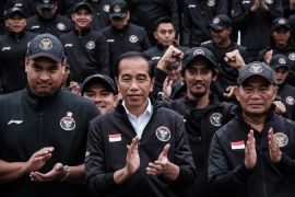 Joko Widodo at an event. He is wearing black and is clapping.