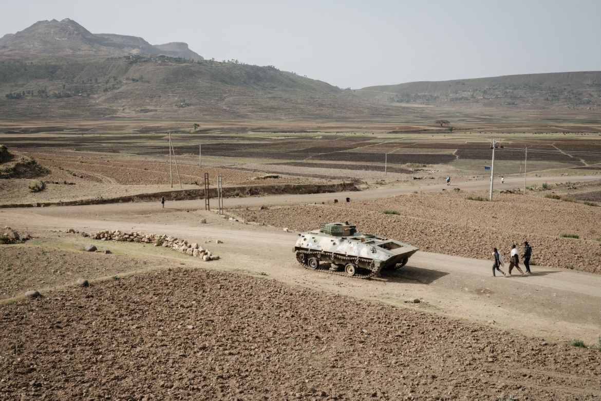 People walk near a tank of alleged Ethiopian army that is abandoned on the road near Dengolat, southwest of Mekele in Tigray region, Ethiopia.