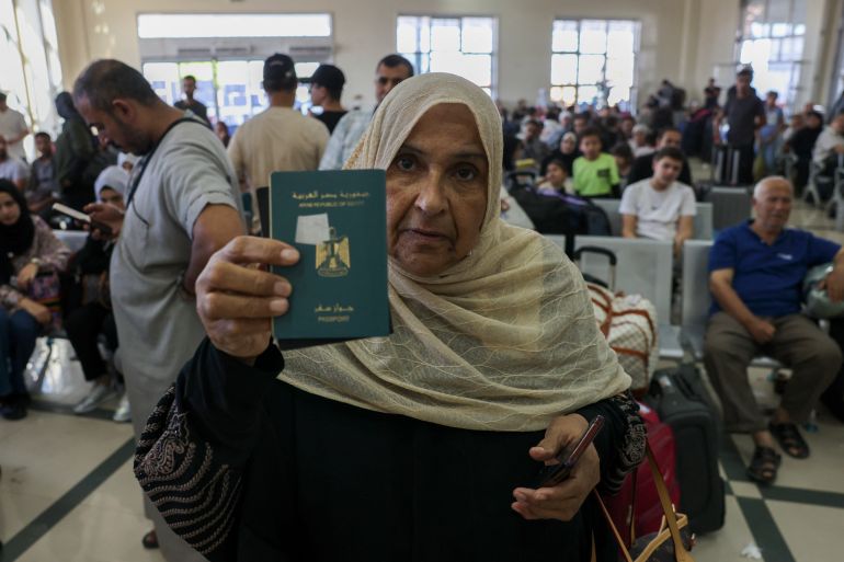A woman shows her Egyptian passport, as Palestinian dual nationals and foreigners wait to cross the Rafah border crossing with Egypt