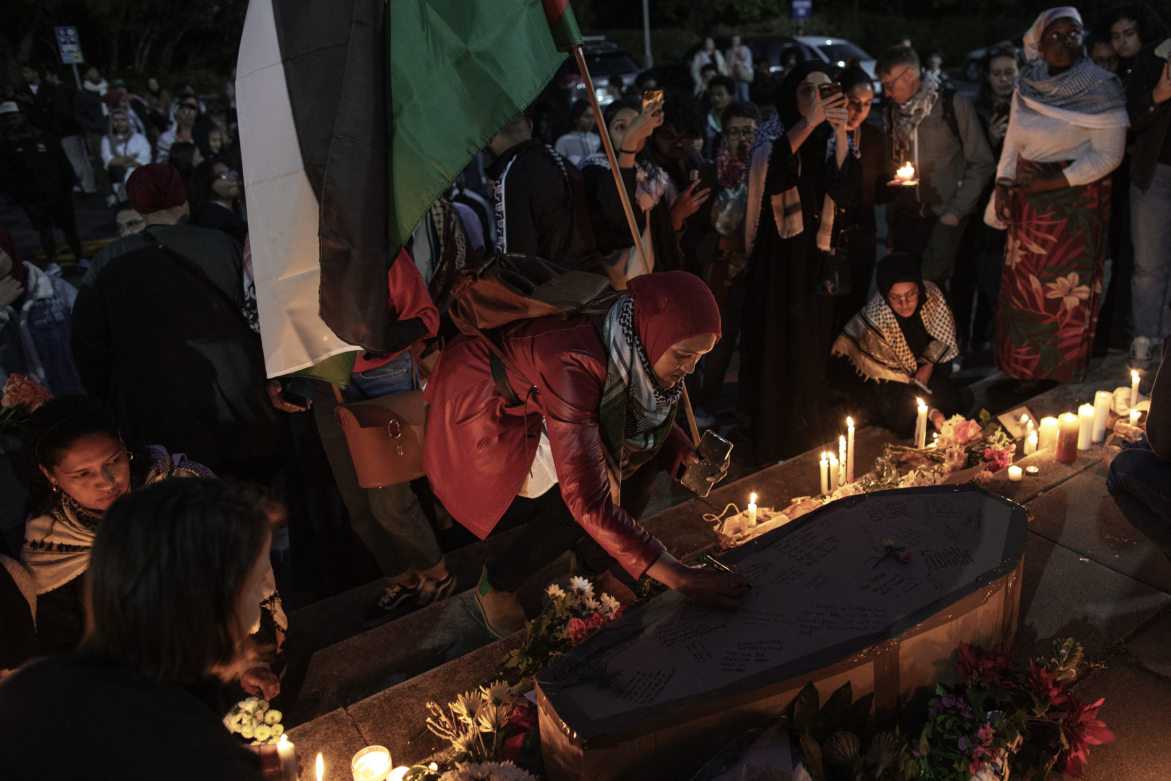 Activists light candles and lay flowers as they write messages on a mock coffin during a vigil event "Honour of All the Palestinian Martyrs" organised by a group of Jewish, Muslim and Christian students at the University of Cape Town lower Campus in Cape Town.