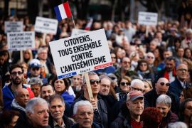 People marching in Paris. One is holding a placard reading 'Citizens together against anti-Semitism'