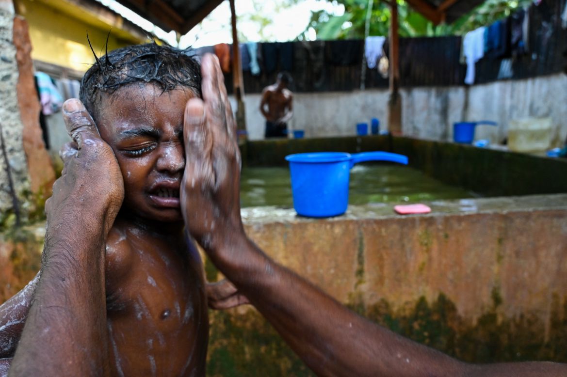 A Rohingya refugee bathes his child following their arrival at a makeshift shelter in Padang Tiji, Indonesia's Aceh province.