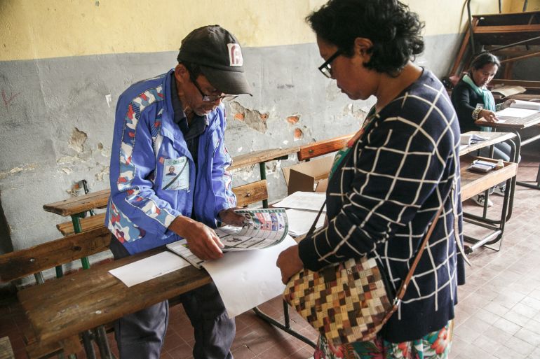 A voter (C) receives her ballot paper from a polling station official at the JJ Rabearivelo polling station in Antananarivo on November 16, 2023, during the first round of the Madagascar presidential election. - Polls opened on November 16, 2023 in Madagascar's presidential election, which is being boycotted by most opposition candidates over concerns about the vote's integrity. (Photo by RIJASOLO / AFP)