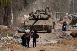 Displaced Palestinians pass an Israeli tank on the southern outskirts of Gaza City [File: Mahmud Hams/AFP]
