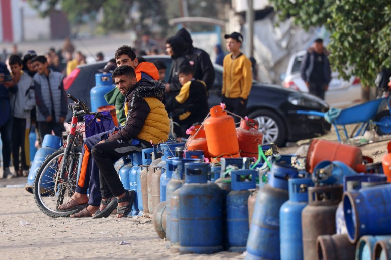young men in brightly coloured jackets sit on blue gas canisters