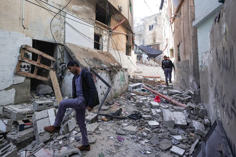 Men walk amid the debris of damaged buildings following an overnight Israeli incursion in the occupied West Bank city of Jenin. [Zain Jaafar/AFP]