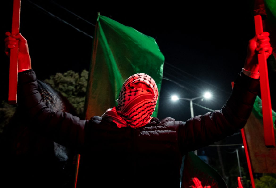 A masked man holds up flags in Ramallah in the occupied West Bank.