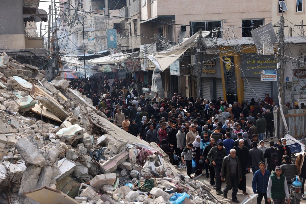 Crowds of locals and displaced Palestinians walk past destroyed buildings in the southern Gaza Strip city of Khan Yunis.