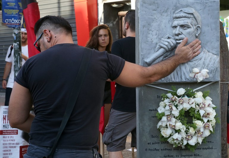 epa06212608 A young man, touches the monument in honour of Greek musician Pavlos Fyssas who was stabbed to death by a member of the ultra-right Golden Dawn party on 18 September 2013, takes part in a march, in Keratsini, western Attica, Greece, 18 September 2017. A protest march and a concert marking the fourth anniversary since the murder of Greek rapper Pavlos Fyssas by members of the far-right party Golden Dawn will be held in the Piraeus suburb of Keratsini where the rapper lived. Four years after the musician's murder, the man that was accused and confessed to his murder, Giorgos Roupakias, has been released from prison with restrictions on his movement, because the maximum period for imprisonment on remand has been exceeded. EPA-EFE/ORESTIS PANAGIOTOU