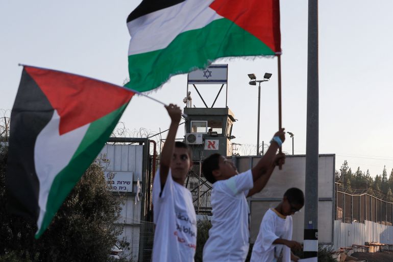 Arab Israelis lift Palestinian flags and placards during a protest outside the Megiddo prison in northern Israel on August 22, 2021, to demand the release of prisoners from their community jailed following clashes with Jewish Israelis in May in Lod and other cities. (Photo by Ahmad GHARABLI / AFP)