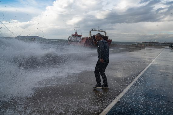 A man tries to protect himself from water while strong winds hit the city of Istanbul on November 30, 2021