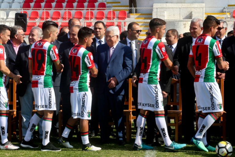 A row of soccer players walk along a line of politicians, shaking hands