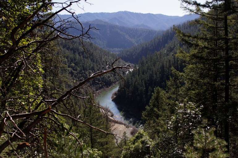 The Klamath River cuts through a green landscape filled with trees and mountains.