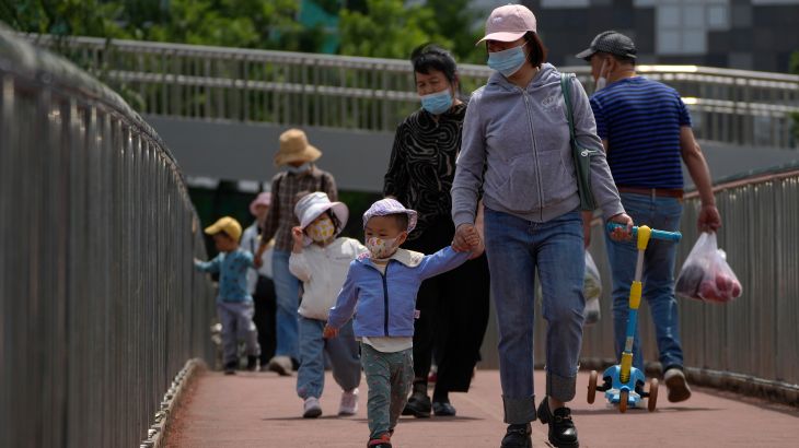 Woman and child in protective masks walk across a bridge.