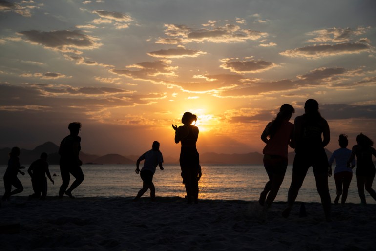 People exercise on he beach as the sun rises