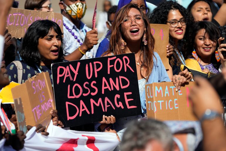 Climate protestors, one holds a sign that reads "Pay up for loss and damage"