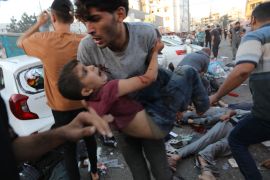 An injured Palestinian boy is carried from the ground following an Israeli airstrike outside the entrance of the al-Shifa hospital in Gaza City
