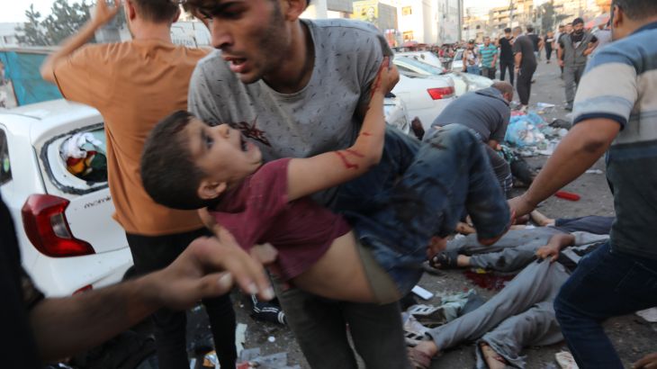 An injured Palestinian boy is carried from the ground following an Israeli airstrike outside the entrance of the al-Shifa hospital in Gaza City