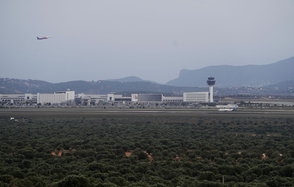 A plane takes off as the olive groves surround the city's international airport, in Spata suburb, east of Athens, Greece.