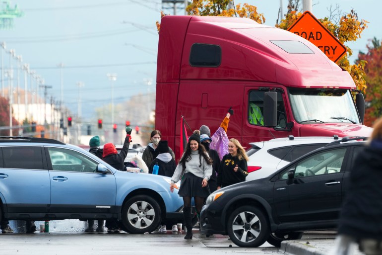 Protesters weave around a blockade of cars, SUVs and trucks at the Port of Tacoma.