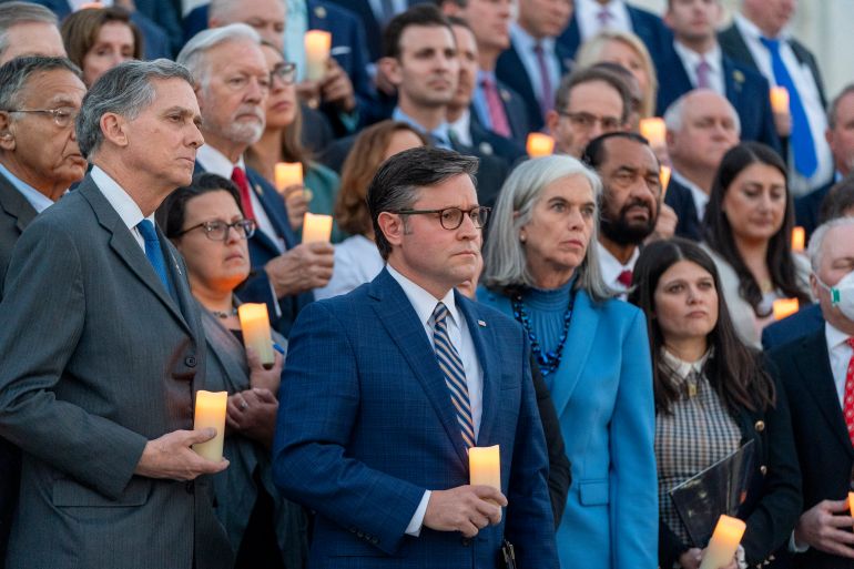 Mike Johnson and other members of Congress stand on the steps of Congress, each holding a small votive candle.